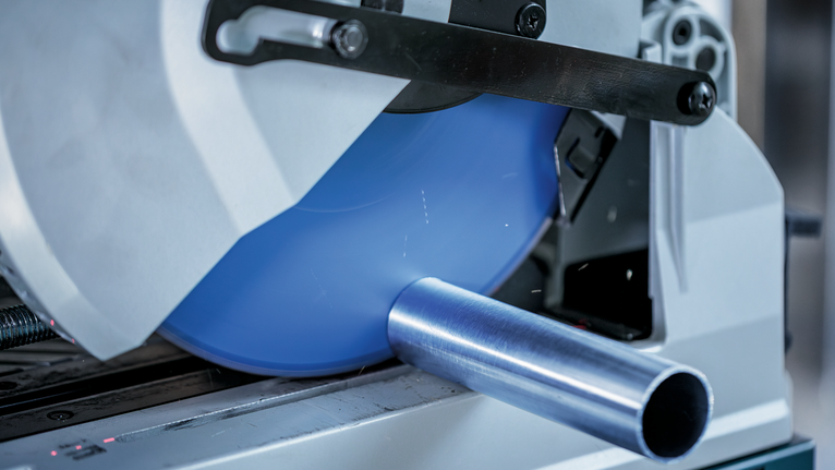 근접 촬영한 산업 현장에서 원형 톱으로 금속 파이프를 절단하는 모습입니다.