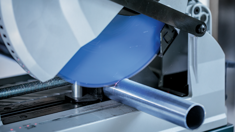 금속 절단 톱은 둥근 금속 파이프를 자르면서 불꽃을 냅니다.