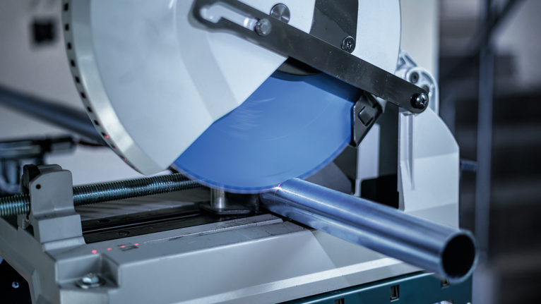 작업장에서 강철 파이프를 절단하는 금속 절단 톱입니다.