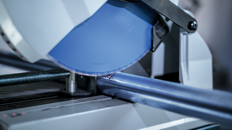 작업장에서 원형 톱으로 금속 파이프를 절단하고 있습니다.