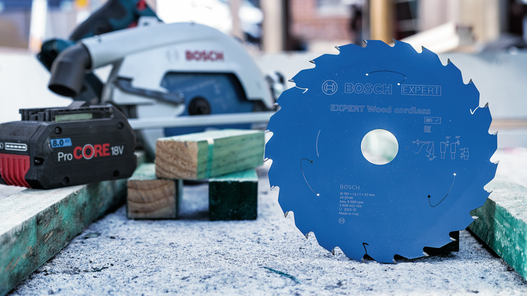 원형 톱날이 무선 배터리와 톱 옆 작업대 위에 똑바로 세워져 있습니다.