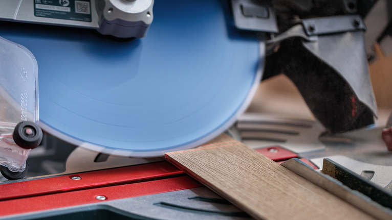 마이터 톱 작업대에서 원형 톱으로 나무판을 자르고 있습니다.