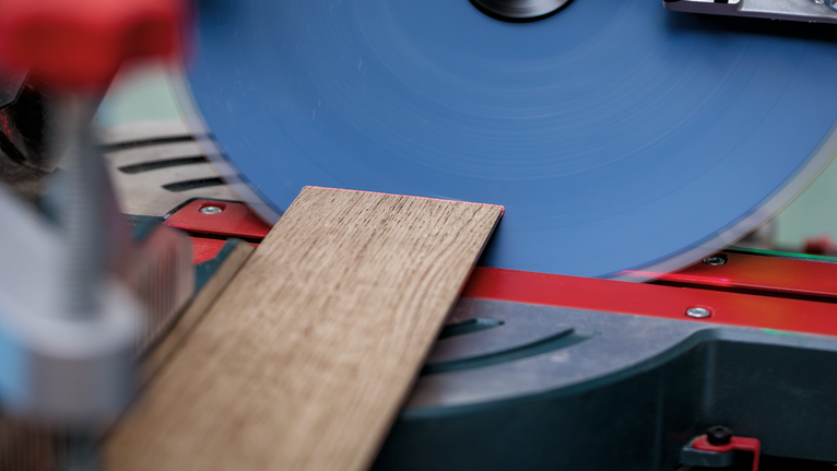 마이터 톱 작업대에서 원형 톱으로 나무 판자를 자르고 있습니다.