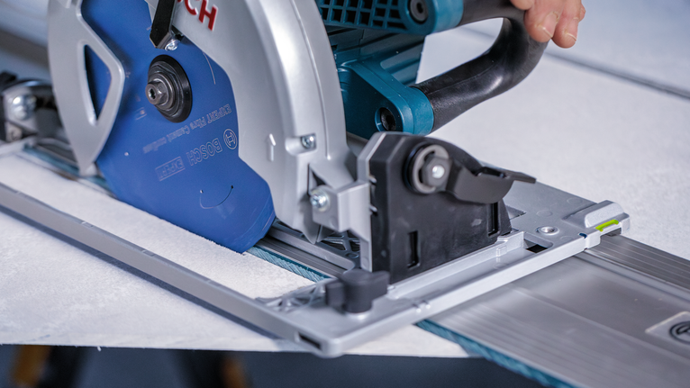 타일을 자르기 위해 원형 톱을 트랙을 따라 안내하는 사람.