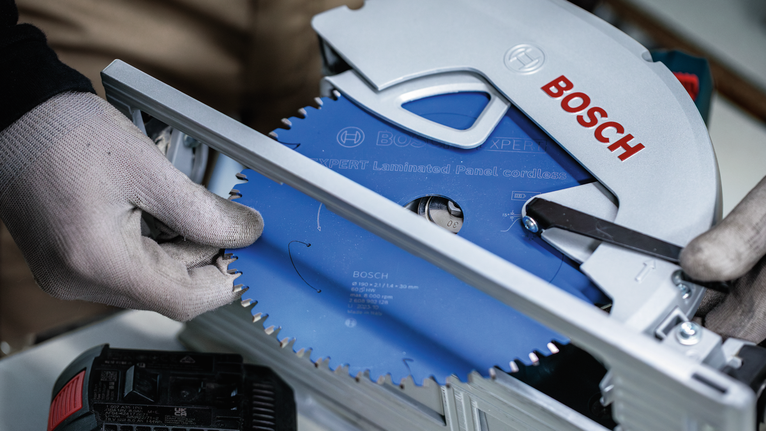 안전 장비를 착용한 사람이 원형 톱날을 조정하고 있습니다.