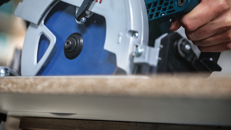 사람이 원형 톱을 사용하여 나무를 자릅니다.