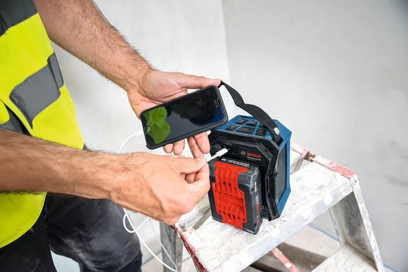 안전 장비를 착용한 사람이 사다리 위에 있는 휴대용 블루투스 스피커에 스마트폰을 연결합니다.