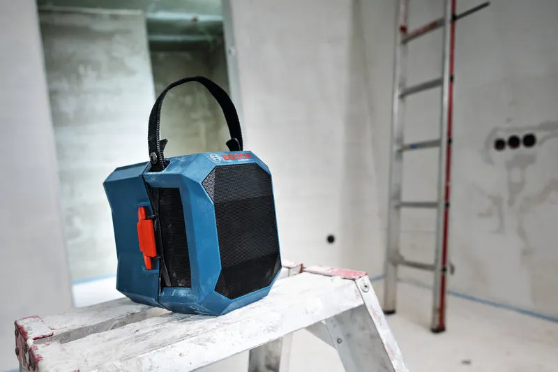 공사 중인 방의 사다리 위에 손잡이가 달린 휴대용 작업 현장용 라디오를 올려놓았습니다.
