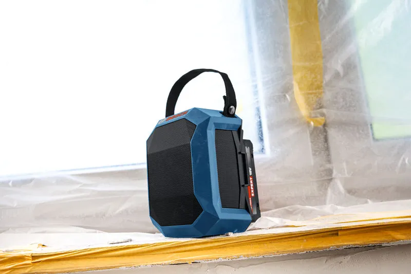 건설 현장 창틀에 손잡이가 달린 파란색 블루투스 스피커가 놓여 있습니다.