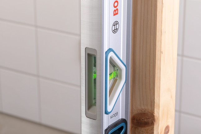 수평기로 수직 목재 들보의 정렬을 측정합니다.