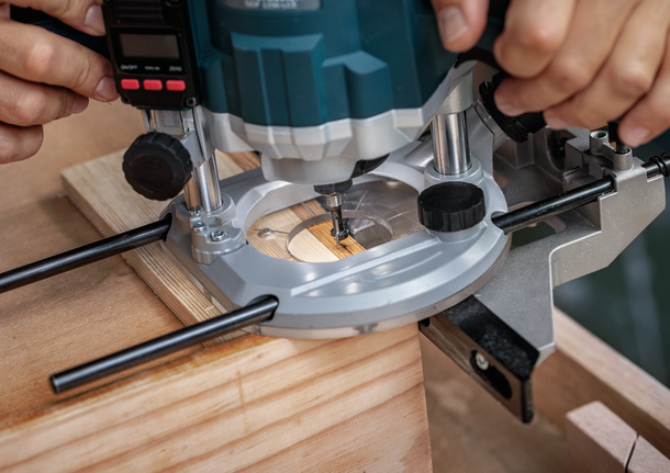 플런지 라우터를 사용하여 나무 조각에 홈을 파는 사람.