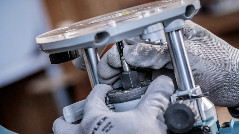 안전 장비를 착용한 사람이 작업장에서 전동 공구를 조금 조정하고 있습니다.