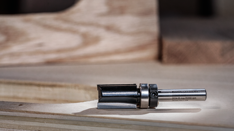 나무 작업대 위에 올려진 금속 라우터 비트입니다.