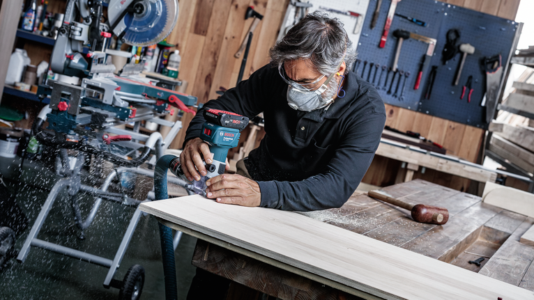 안전 장비를 착용한 사람이 나무판 위에서 무선 라우터를 사용하고 있습니다.