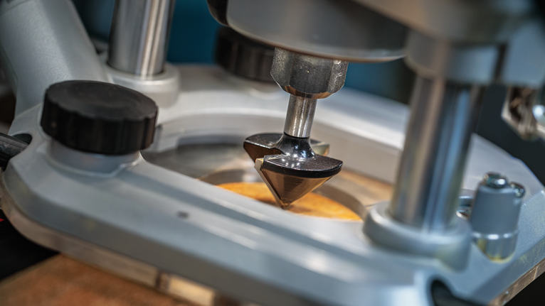 작업대 위의 나무 표면에 라우터 비트를 조각하는 모습입니다.