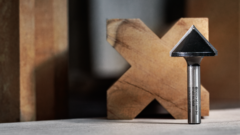 나무 블록 앞 작업대에 세워진 챔퍼 라우터 비트입니다.