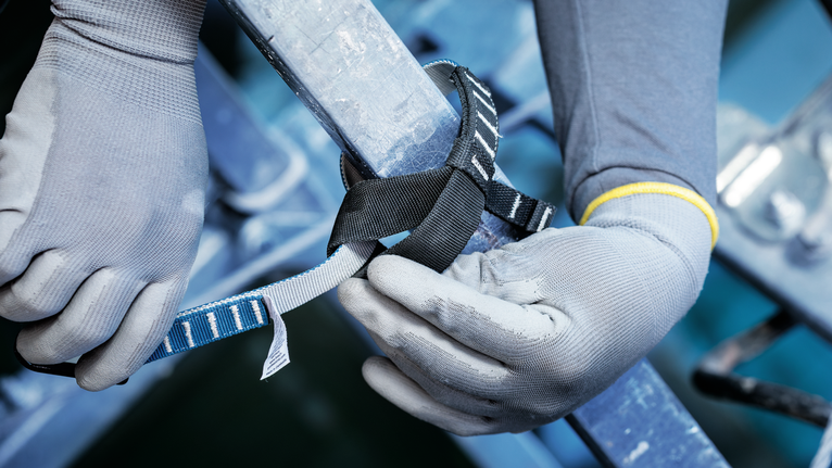 안전 장비를 착용한 사람이 금속 난간 주위에 안전띠를 고정합니다.