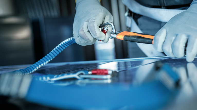 안전 장비를 착용한 사람이 안전 하네스에 카라비너를 부착합니다.