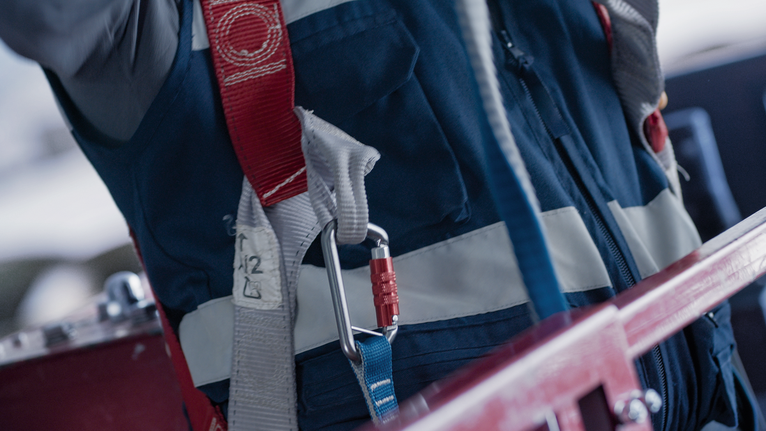 하네스와 카라비너로 고정된 안전 장비를 착용한 사람입니다.