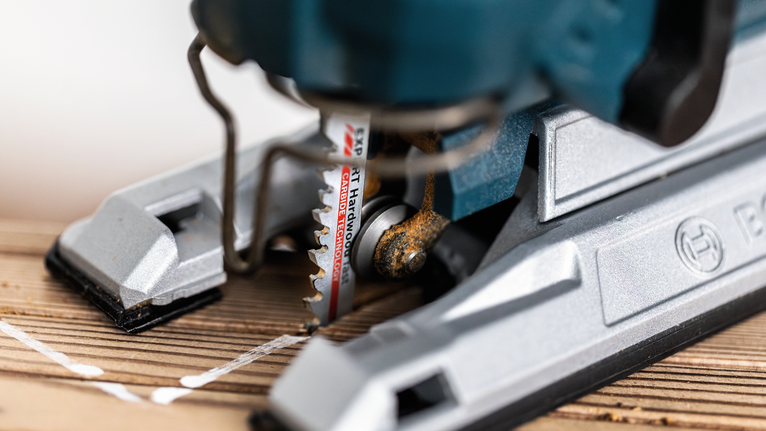 나무판에 표시된 선을 따라 퍼즐을 자르는 모습입니다.