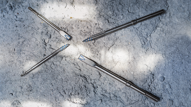 거친 콘크리트 표면에 배열된 4개의 금속 드릴 비트.