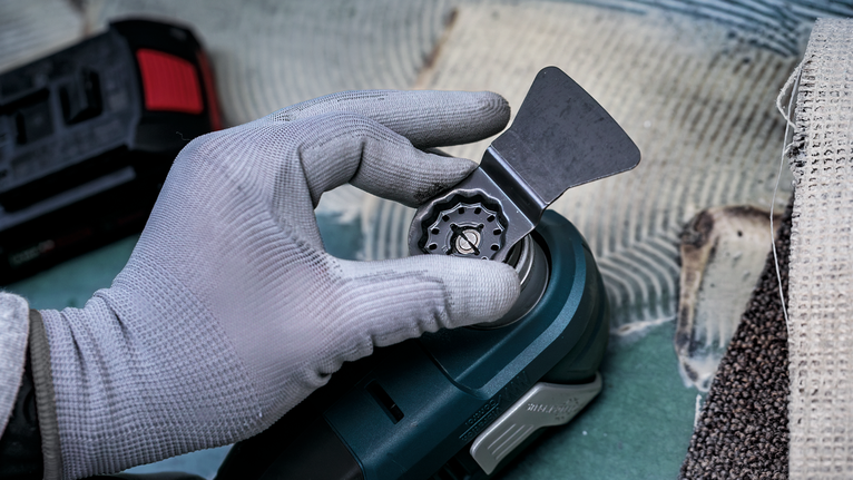 안전 장비를 착용한 사람이 전동 공구에 날을 부착하고 있습니다.