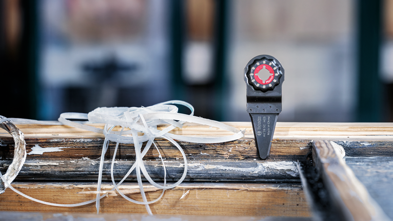 낡은 나무 창틀에 장착된 진동식 다용도 공구 날 부착물.