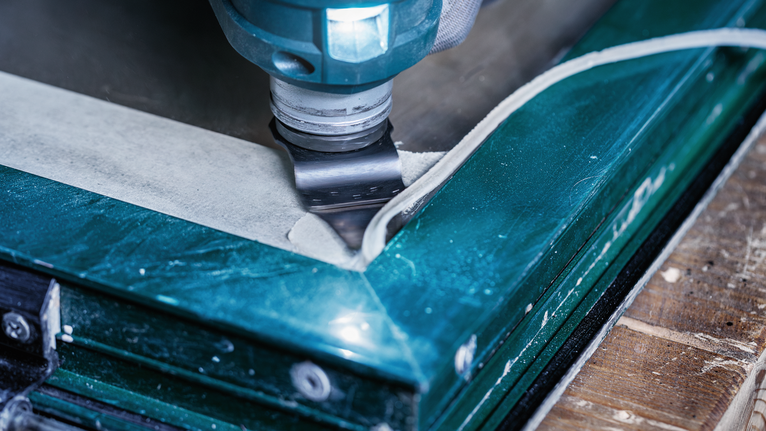 진동 공구가 창틀 실리콘을 절단하고 있습니다.