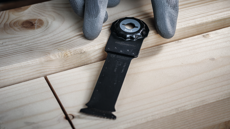 안전 장비를 착용한 사람이 나무 표면에 절단용 칼날을 위치시키고 있습니다.