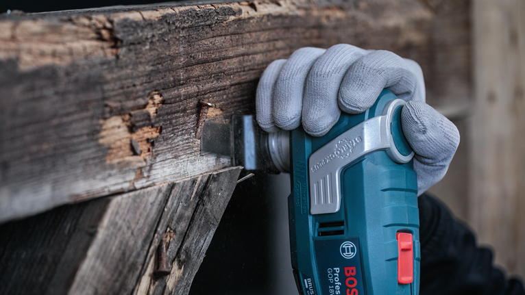 안전 장비를 착용한 사람이 전동 공구를 사용하여 나무 기둥을 자르고 있습니다.