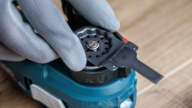 안전 장비를 착용한 사람이 전동 공구의 부속품을 조절하고 있습니다.