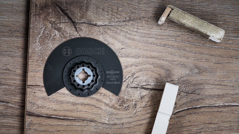 원형톱날이 나무 표면 위에 놓여 있고, 주변에는 포장재가 있다.