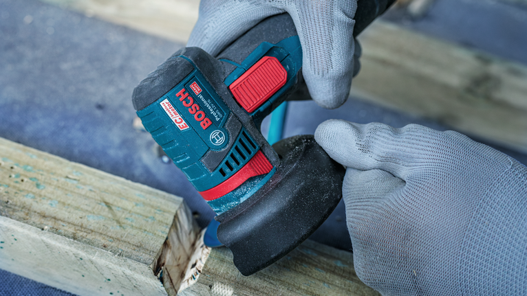 안전 장비를 착용한 사람이 각도 그라인더를 사용하여 나무 표면을 연마하고 있습니다.