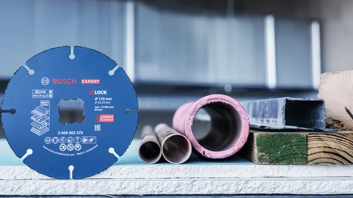 금속 파이프와 건축 자재 옆에 원형 톱날이 세로로 전시되어 있습니다.