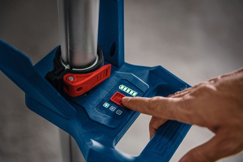 한 사람이 디지털 제어판을 사용하여 무선 작업 현장 조명을 조정하고 있습니다.