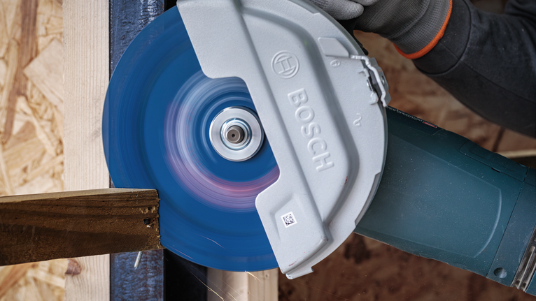 안전장비를 착용한 사람이 원형 톱으로 나무를 자릅니다.