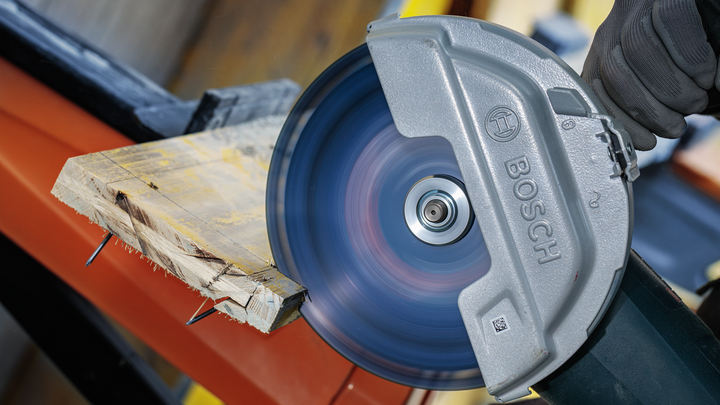 안전 장비를 착용한 사람이 원형 톱을 사용하여 나무 판자를 자르고 있습니다.