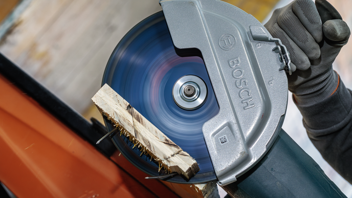 안전 장비를 착용한 사람이 원형 톱으로 나무를 자릅니다.