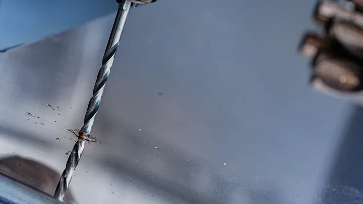 사람이 금속판에 구멍을 뚫습니다.