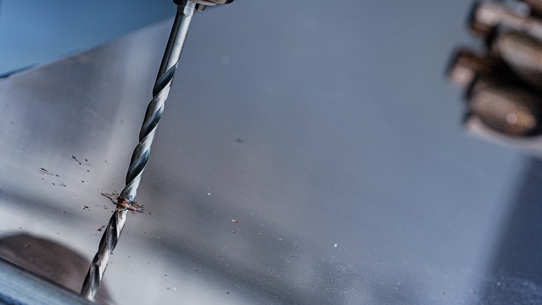 사람이 금속판에 구멍을 뚫습니다.