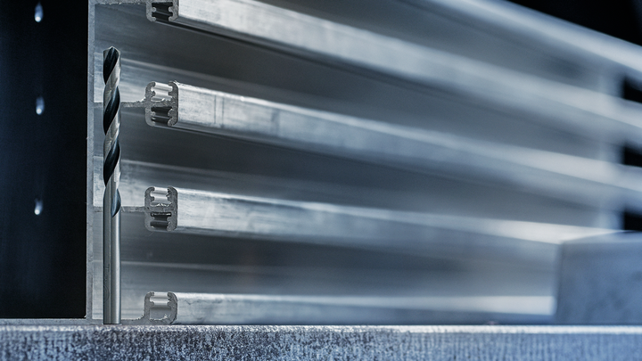 쌓인 알루미늄 프로파일 앞에 금속 드릴 비트를 배치했습니다.