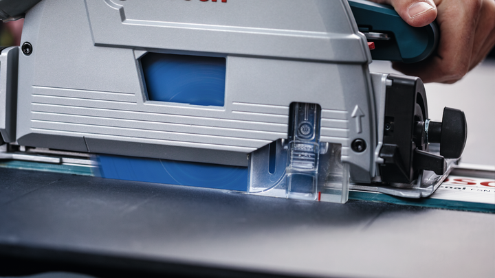 사람이 원형 톱을 궤도를 따라 움직여 나무 조각을 자릅니다.