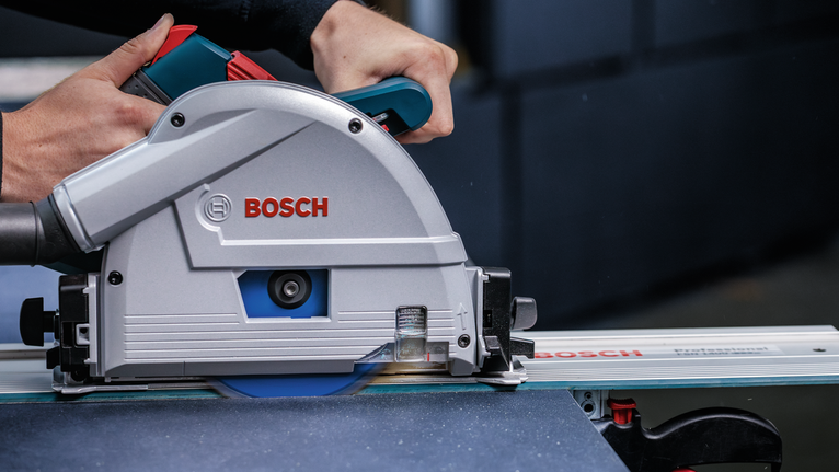 사람이 원형 톱을 궤도를 따라 움직여서 재료 시트를 자릅니다.