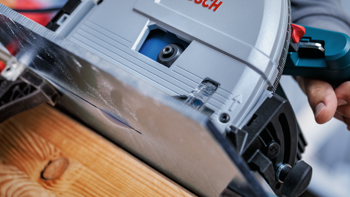 사람이 나무판을 따라 원형 톱을 움직입니다.