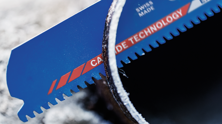 탄화물 날이 달린 톱날이 금속 파이프를 절단하고 있다.