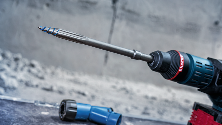 벽 가까이에 끌 모양의 드릴 비트를 장착한 회전 해머 드릴.