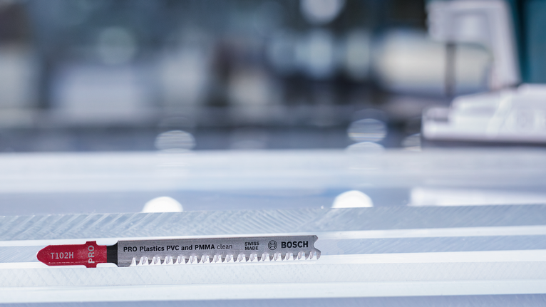 플라스틱 절단용 직소 날이 줄무늬 작업대 위에 놓여 있다.