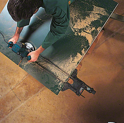 작업자가 전기톱을 조작하여 나무판을 자릅니다.