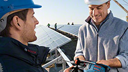 두 명의 남자가 태양광 패널 옆에서 보쉬 전동 공구를 가지고 대화하고 있다.