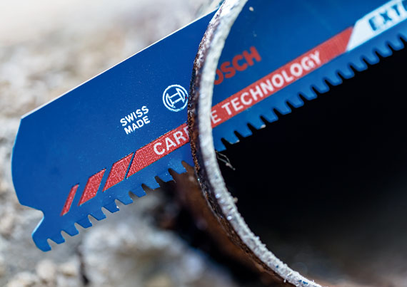 보쉬 전문 카바이드 톱날이 금속 파이프 옆에 놓여 있다.